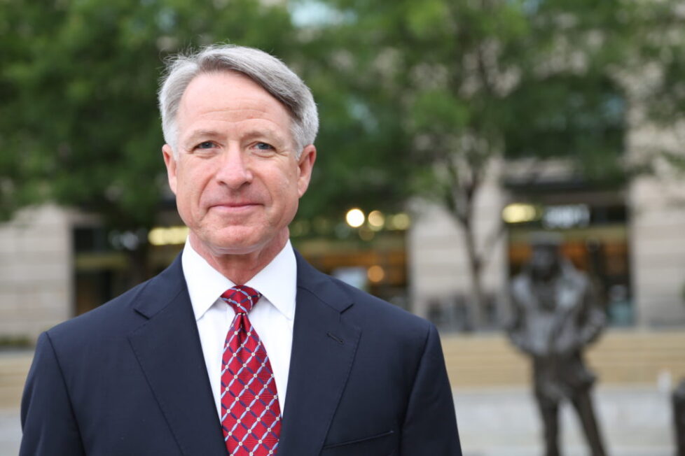 A man in suit and tie standing outside.